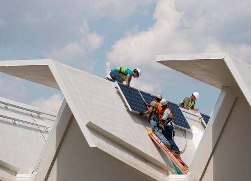 Construction workers install solar-PV panels